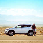 man standing next to car in desert