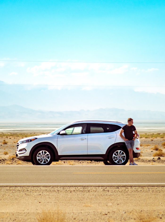 man standing next to car in desert