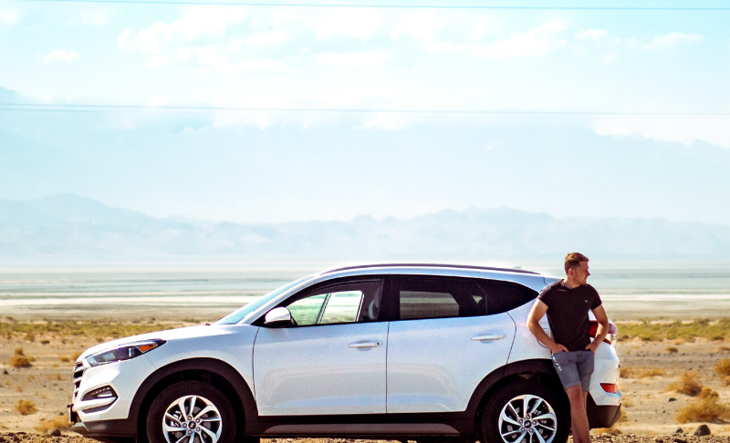 man standing next to car in desert