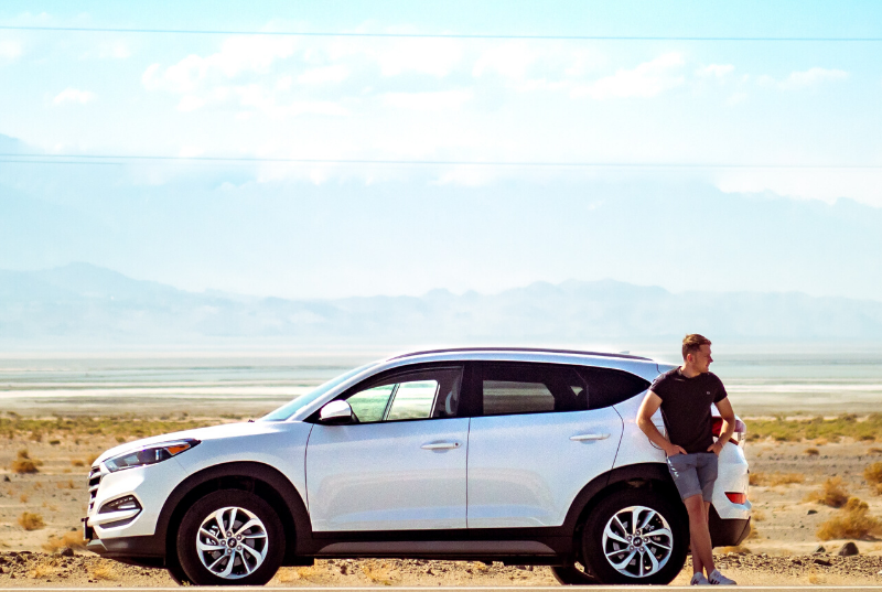 man standing next to car in desert